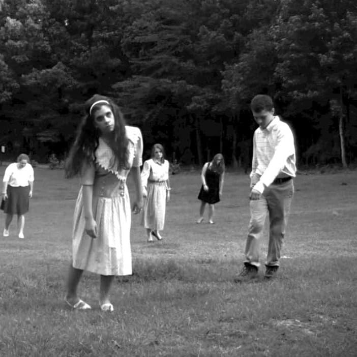 Zombies in a field, swaying in a black and white photo.